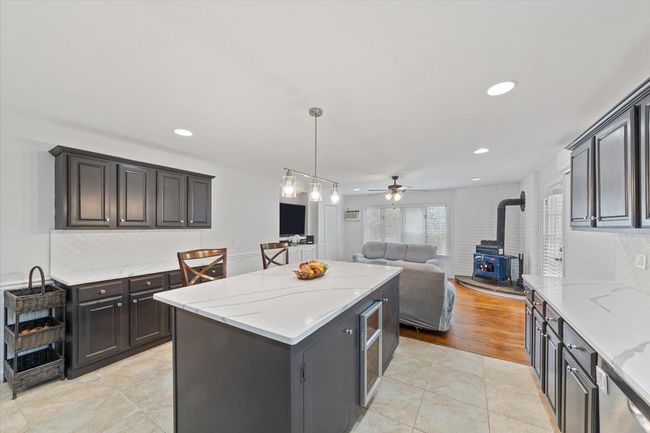 Kitchen with open floor plan, a wood stove, a center island, decorative backsplash, and ceiling fan | Image 32