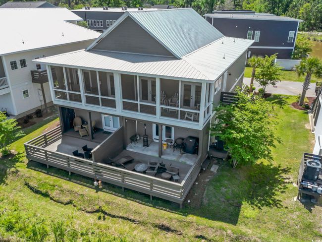 Rear view of property featuring a wooden deck, a sunroom, metal roof, and french doors | Image 34