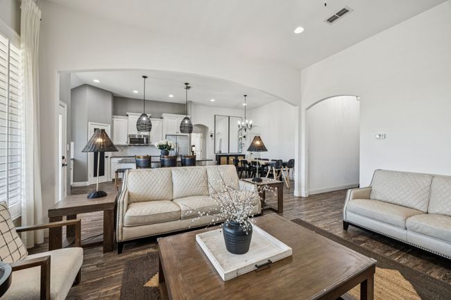 Living room with arched walkways, recessed lighting, dark wood-style floors, and a chandelier | Image 4