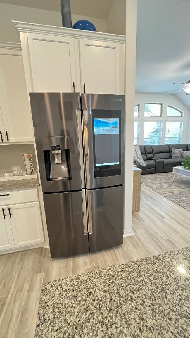 Kitchen featuring stainless steel fridge with ice dispenser, light wood finished floors, a ceiling fan, white cabinetry, and vaulted ceiling | Image 10