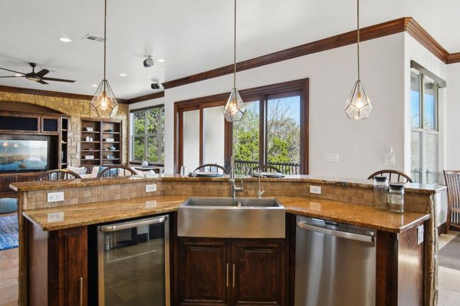 Kitchen with ornamental molding, a sink, light stone counters, open floor plan, and dishwasher | Image 14