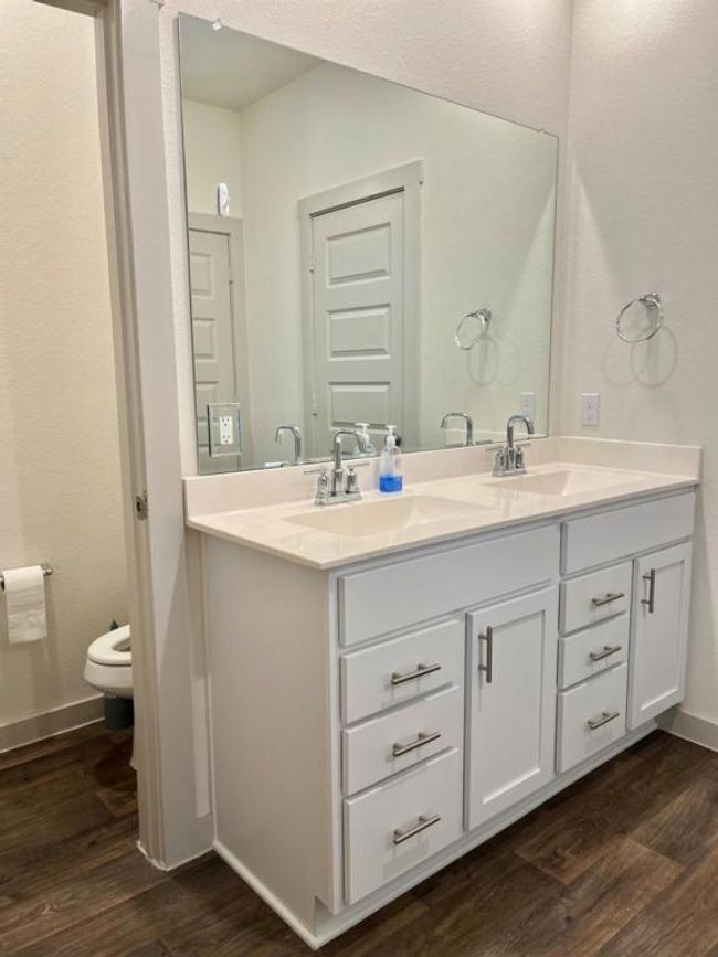 Bathroom featuring double vanity, wood finished floors, toilet, and baseboards | Image 13