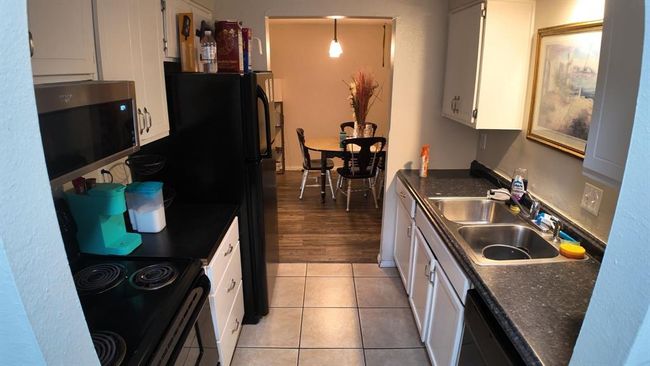 Kitchen with stainless steel microwave, dark countertops, white cabinets, black electric range, and dishwasher | Image 4
