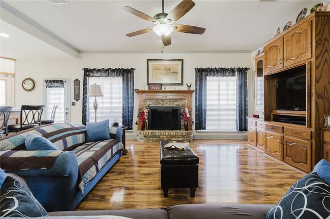 Living room featuring a fireplace, ornamental molding, light hardwood / wood-style floors, and ceiling fan | Image 14