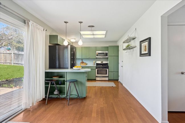 Kitchen featuring wood finished floors, visible vents, a peninsula, stainless steel appliances, and green cabinets | Image 7
