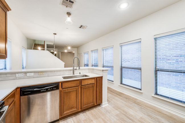 Kitchen with dishwasher, brown cabinets, a peninsula, and light countertops | Image 12
