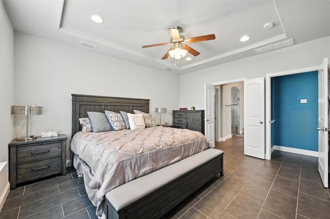 Downstairs Primary Bedroom with a tray ceiling, recessed lighting, dark tile patterned floors, and a ceiling fan | Image 16