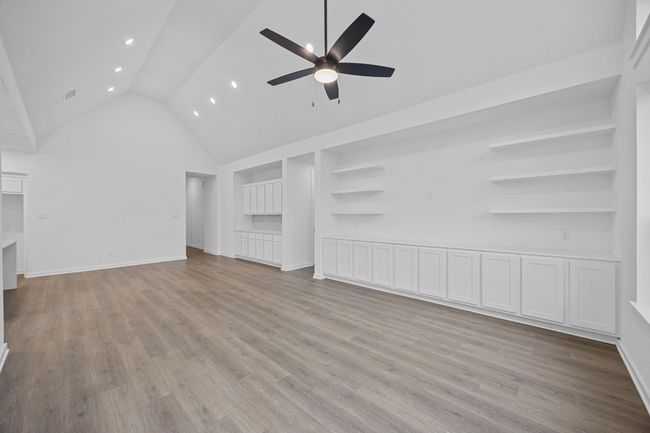 Unfurnished living room with ceiling fan, high vaulted ceiling, light wood-style flooring, built in features, and recessed lighting | Image 10