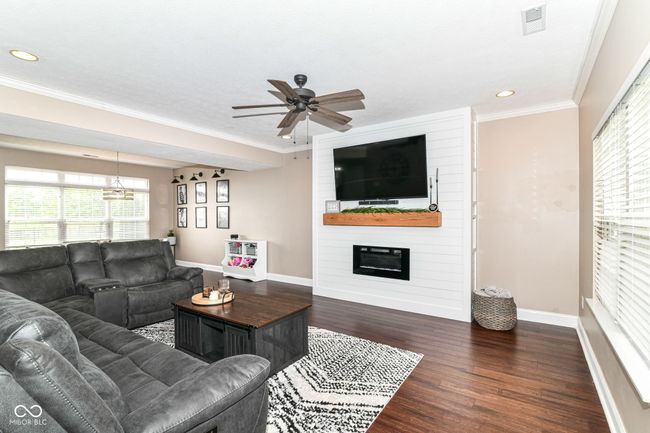 living room featuring baseboards, plenty of natural light, dark wood-style floors, a ceiling fan, and crown molding | Image 6