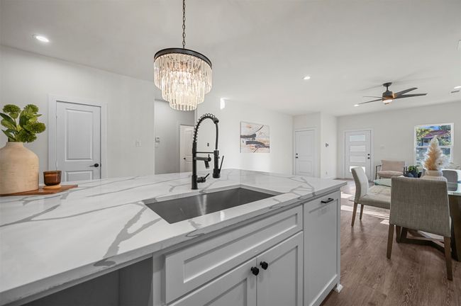 Kitchen with a sink, dark wood-style flooring, recessed lighting, ceiling fan with notable chandelier, and hanging light fixtures | Image 15