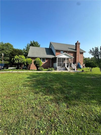 Rear view of property featuring a sunroom and a lawn | Image 1