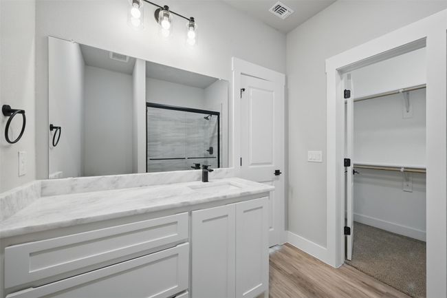 Bathroom featuring a stall shower, vanity, wood finished floors, a walk in closet, and visible vents | Image 12