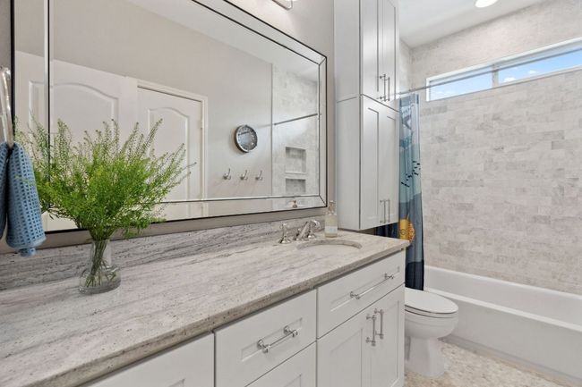 The full secondary bathroom is also tastefully updated with a spacious granited topped vanity and a shower/tub combo with tub-to-ceiling tile backsplash. | Image 28