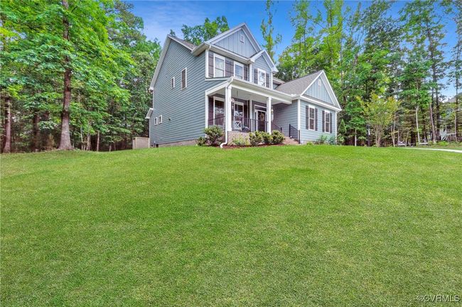 Side view of home showcasing expansive front yard and wooded backdrop. | Image 33