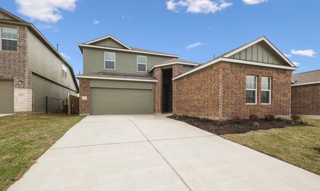 View of front facade featuring board and batten siding, brick siding, an attached garage, and driveway | Image 4