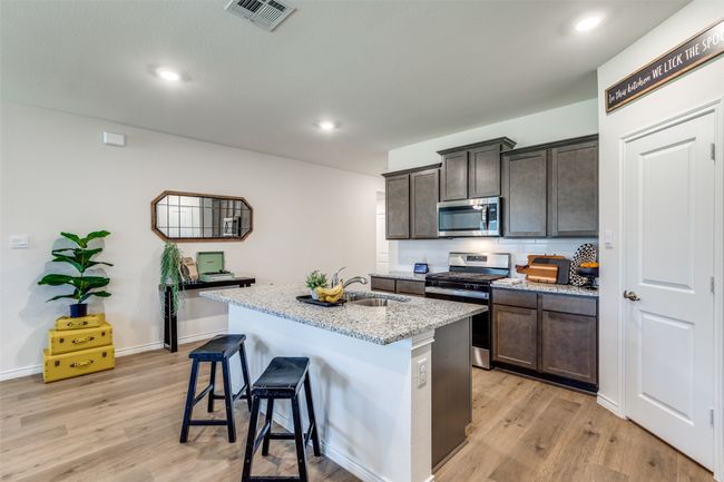 Kitchen View 3 featuring appliances with stainless steel finishes, light laminated wood plank flooring, a breakfast bar on island. | Image 9