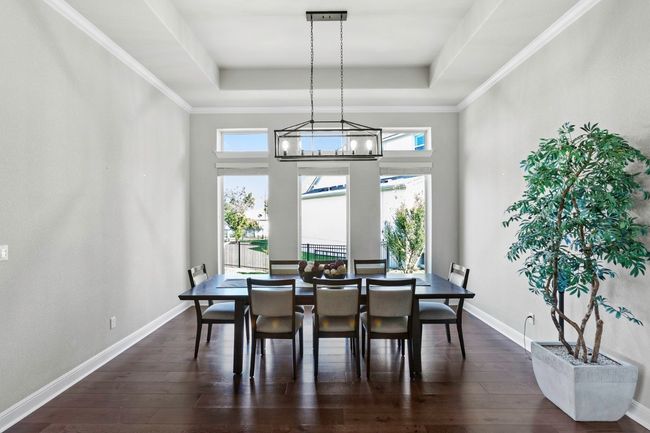Dining space featuring a tray ceiling, dark wood floors, and a chandelier | Image 10