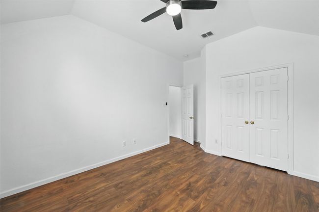 Unfurnished bedroom featuring lofted ceiling, a closet, dark wood-style flooring, baseboards, and a ceiling fan | Image 11
