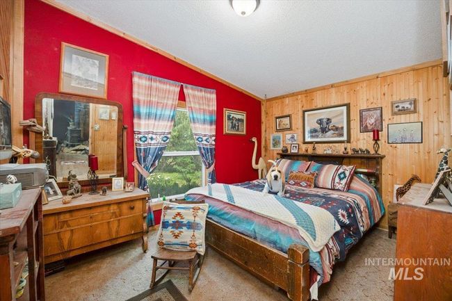Carpeted bedroom featuring lofted ceiling, crown molding, a textured ceiling, and wooden walls | Image 23