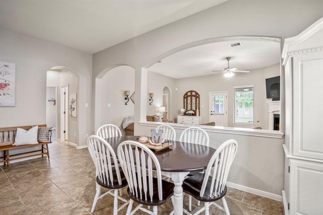 Just steps from the kitchen, the dining area welcomes plenty of natural light. To the left, an arched doorway opens to a hallway leading to two bedrooms, creating a thoughtful and connected floor plan. | Image 11