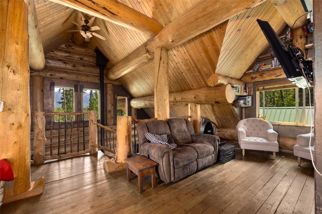 Living room with wood ceiling, wood-type flooring, rustic walls, and a ceiling fan | Image 21