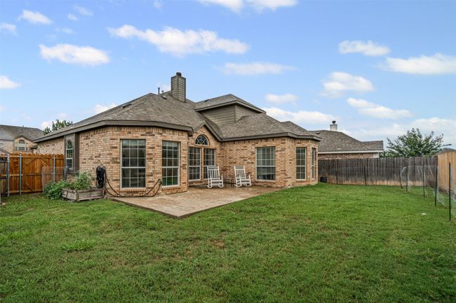 Rear view of house featuring brick siding, a shingled roof, a fenced backyard, and a patio | Image 31