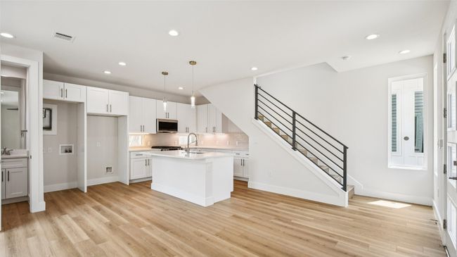 Kitchen featuring hanging light fixtures, recessed lighting, a kitchen island with sink, white cabinetry, and stainless steel microwave | Image 8