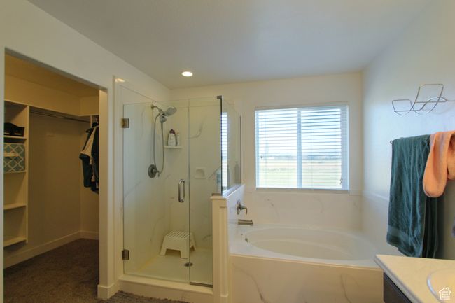 Full bath featuring a bath, a shower stall, vanity, a walk in closet, and recessed lighting | Image 18