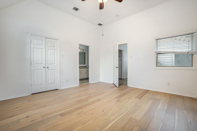 Unfurnished bedroom with baseboards, light wood-type flooring, ensuite bathroom, a high ceiling, and visible vents | Image 12