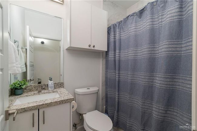 Bathroom with toilet, a shower with shower curtain, and vanity | Image 10