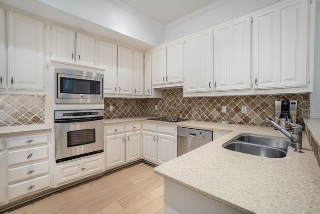 Kitchen featuring light wood-style floors, ornamental molding, a sink, stainless steel appliances, and backsplash | Image 6