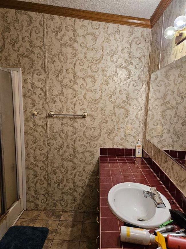 Bathroom with tile patterned flooring, crown molding, a textured ceiling, a shower with shower door, and sink | Image 34
