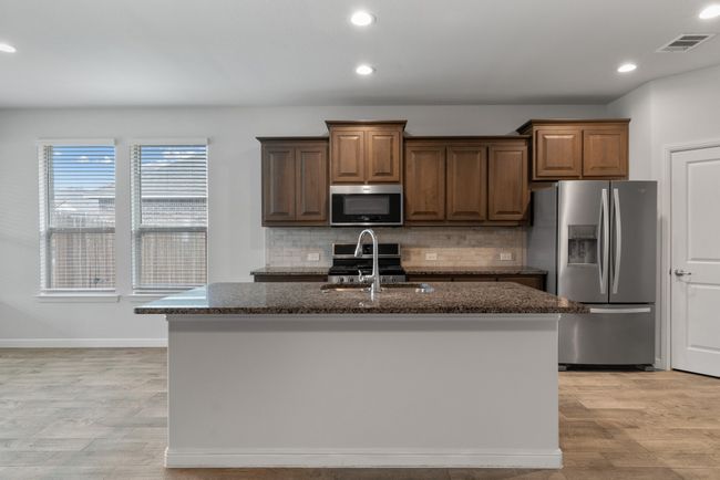 Kitchen with decorative backsplash, visible vents, dark stone counters, stainless steel appliances, and a sink | Image 6