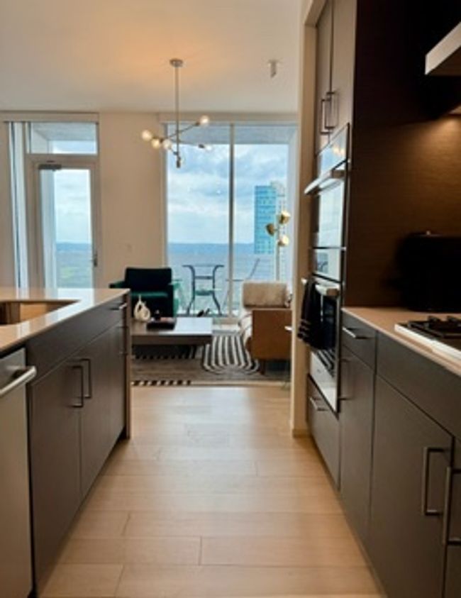 Kitchen with stainless steel appliances, light wood-style floors, an office area, decorative light fixtures, and a chandelier | Image 15