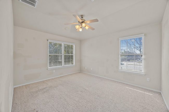 Carpeted empty room featuring baseboards, plenty of natural light, visible vents, and a ceiling fan | Image 17