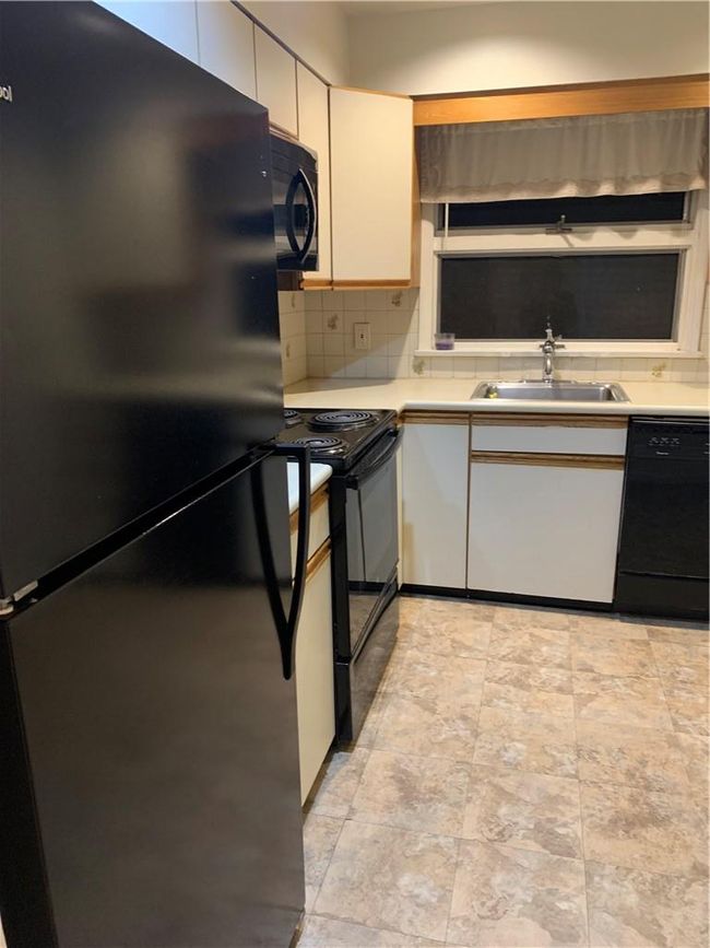 1st Fl Kitchen featuring dishwasher, black / electric stove, sink, white cabinetry, and refrigerator | Image 22