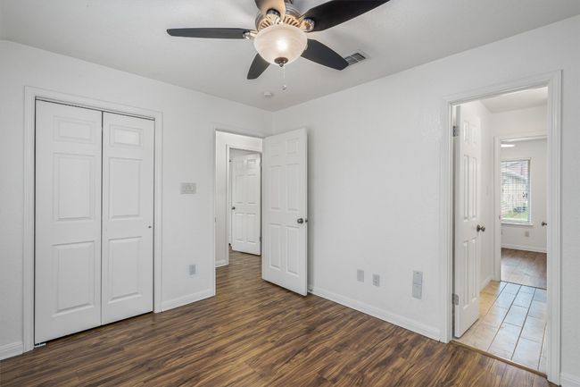 Unfurnished bedroom with ceiling fan, baseboards, wood finished floors, visible vents, and a closet | Image 26