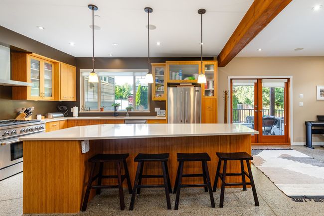 Kitchen featuring stainless steel appliances, light countertops, french doors, a kitchen island, and glass insert cabinets | Image 8