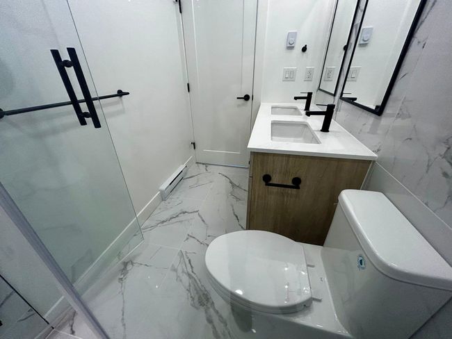 Bathroom with a baseboard heating unit, double vanity, marble finish floor, toilet, and baseboards | Image 18