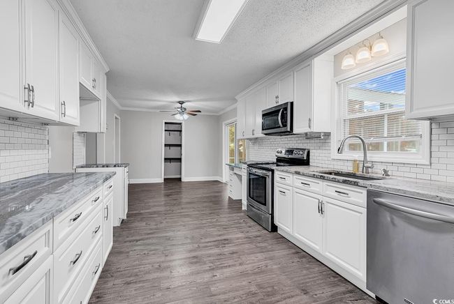 Kitchen featuring stainless steel appliances, white cabinetry, tasteful backsplash, a ceiling fan, and a textured ceiling | Image 14