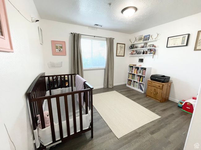 Generous guest bedroom with a textured ceiling and wood finished floors | Image 17