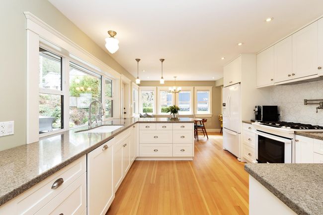 Kitchen with tasteful backsplash, light wood-type flooring, white cabinets, white appliances, and a sink | Image 6