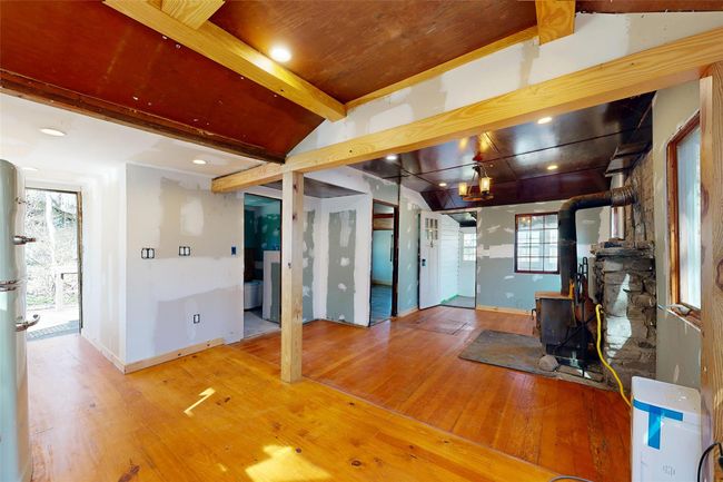 Living room with baseboards, a wood stove, wood finished floors, and a wealth of natural light | Image 8
