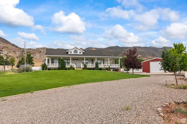 Farmhouse inspired home featuring a mountain view, an outdoor structure, gravel driveway, a porch, and a front yard | Image 94