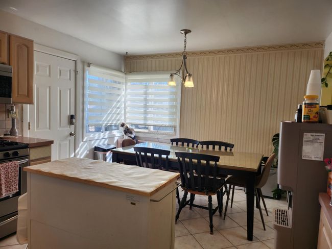 Kitchen with hanging light fixtures, a center island, appliances with stainless steel finishes, butcher block counters, and light tile patterned flooring | Image 5