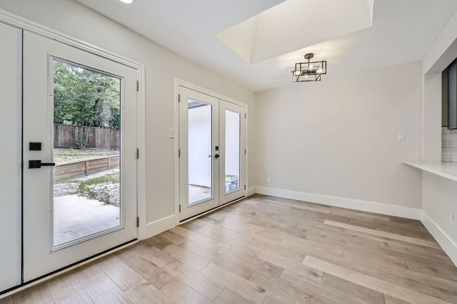 Doorway with a notable chandelier, light wood-style flooring, french doors, and baseboards | Image 13