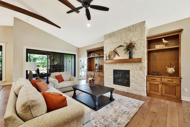 Living room with a stone fireplace, lofted ceiling, light hardwood / wood-style floors, and ceiling fan | Image 9