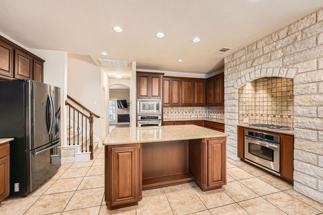 Kitchen featuring visible vents, arched walkways, appliances with stainless steel finishes, and a center island | Image 15