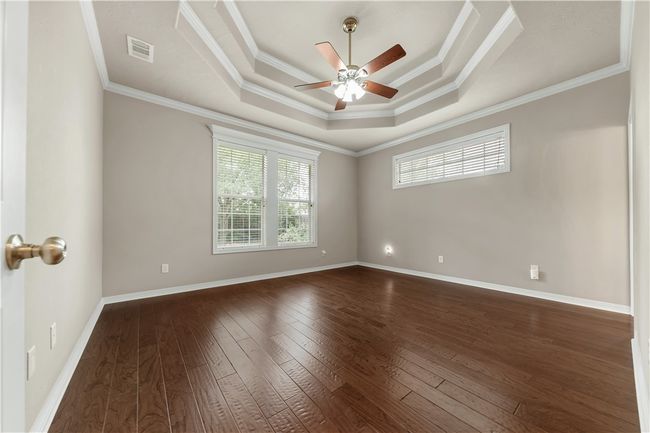 Spare room with ceiling fan, dark wood-type flooring, crown molding, a raised ceiling, and baseboards | Image 19