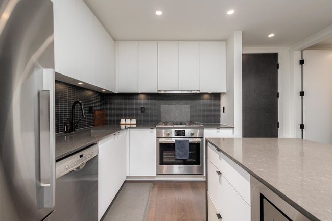 Kitchen featuring appliances with stainless steel finishes, dark wood finished floors, decorative backsplash, modern cabinets, and recessed lighting | Image 13